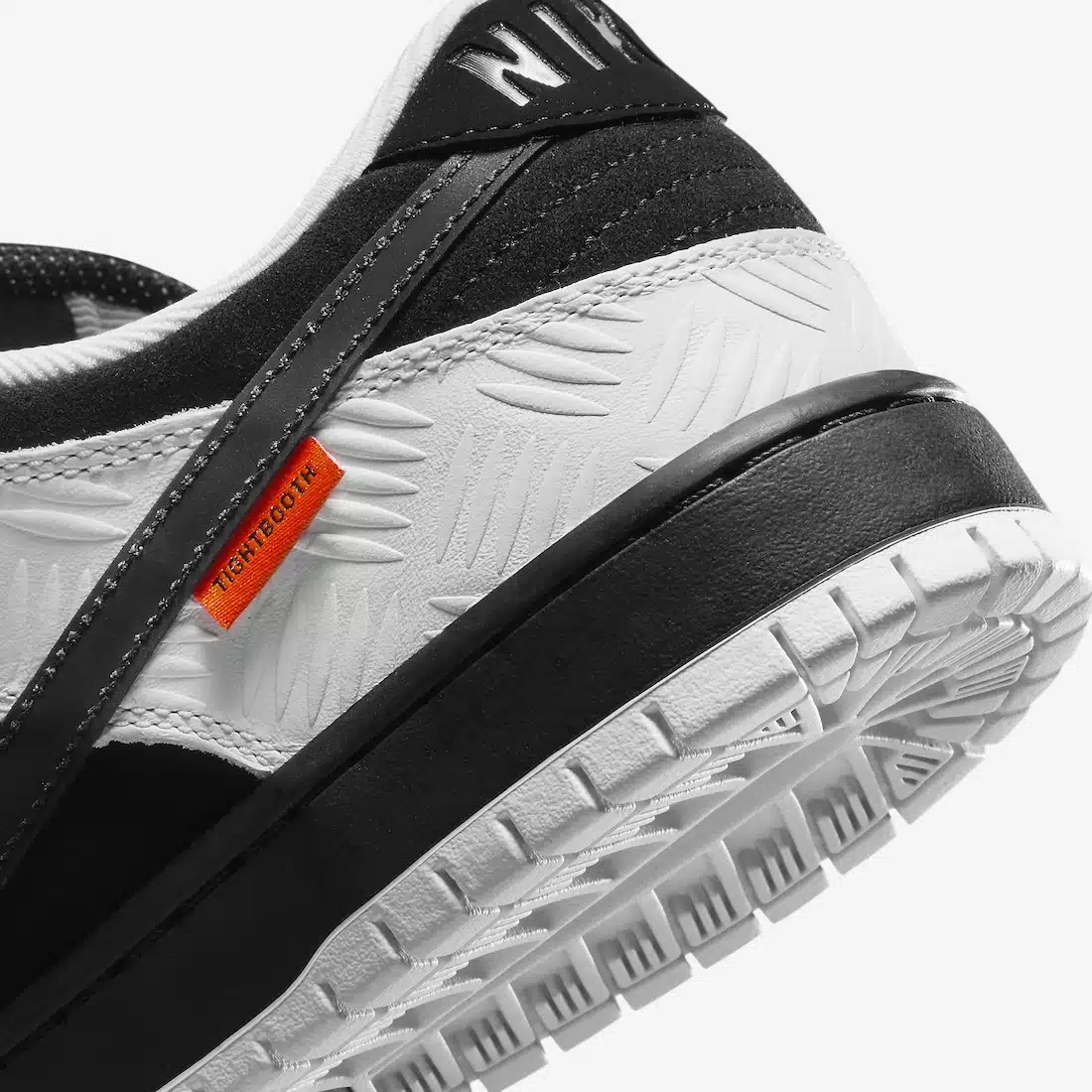 Nike SB Dunk Low TIGHTBOOTH - Vue latérale de la sneaker noir et blanc avec swoosh gris, détail orange sécurité et semelle noire