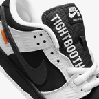 Nike SB Dunk Low TIGHTBOOTH - Vue latérale de la sneaker noir et blanc avec swoosh gris, détail orange sécurité et semelle noire
